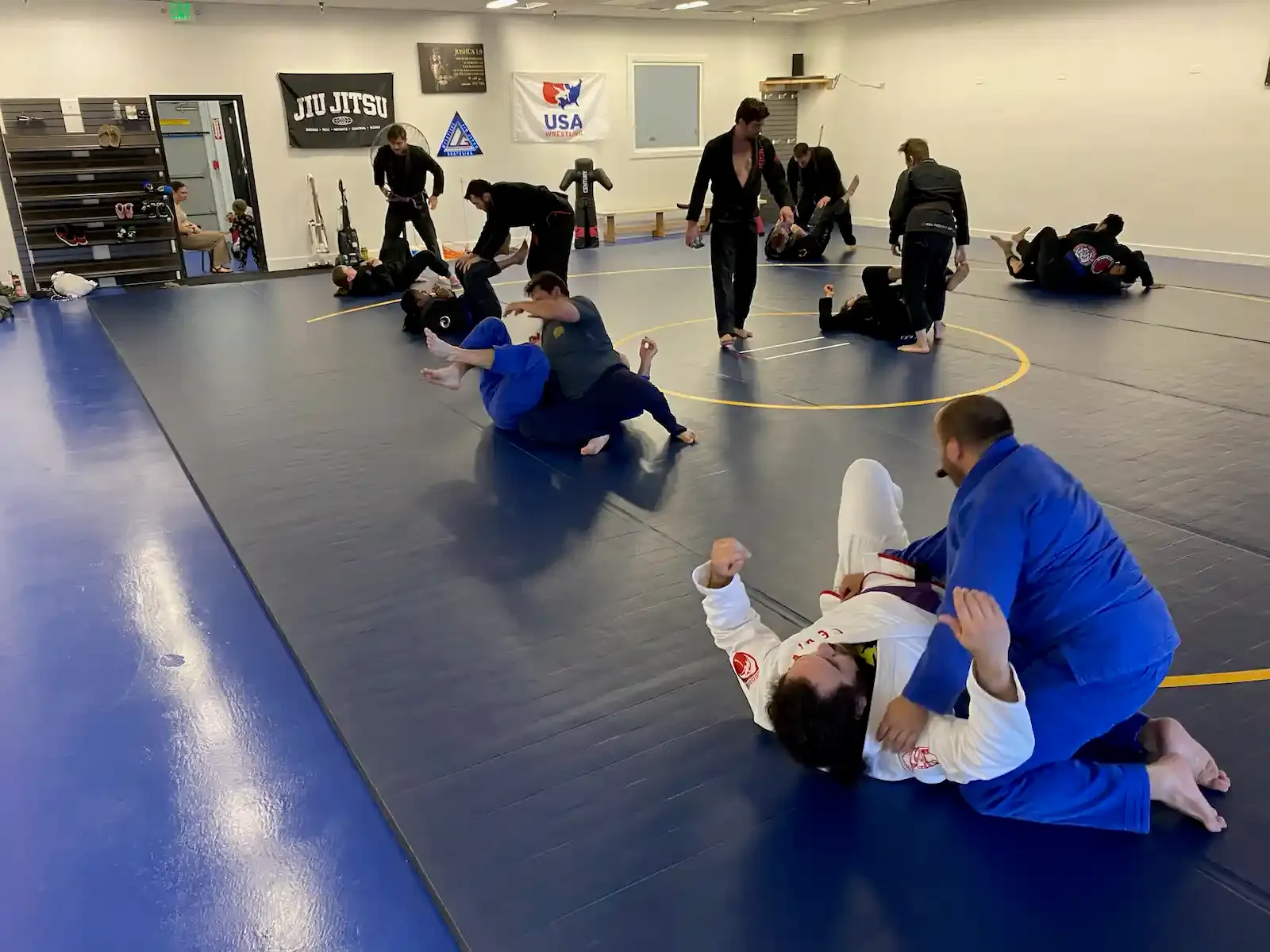 rolling during a bjj class while the instructor watches from the middle of the mat